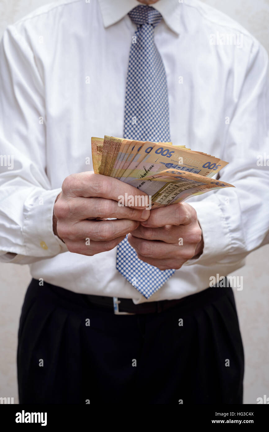 Corrotto imprenditore o politico, conteggio e offrendo un grivna banconote corrompere, in Ucraina Foto Stock