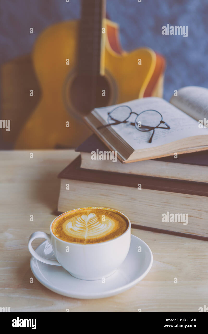 Una tazza di caffè con strumento musicale e di un libro di musica su tavola Foto Stock
