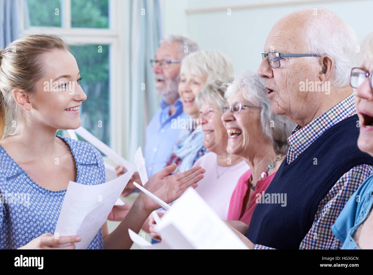 Gruppo di anziani con insegnante a cantare in coro insieme Foto Stock