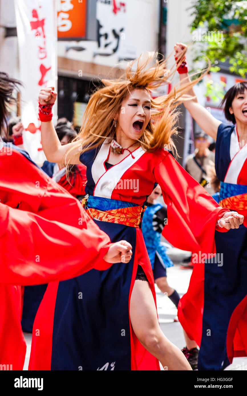 Yosakoi festival. Le donne giapponesi ballerino tinti con i capelli rossi, dancing in città shopping arcade, agitando con i suoi capelli battenti, movimento sfocato Foto Stock