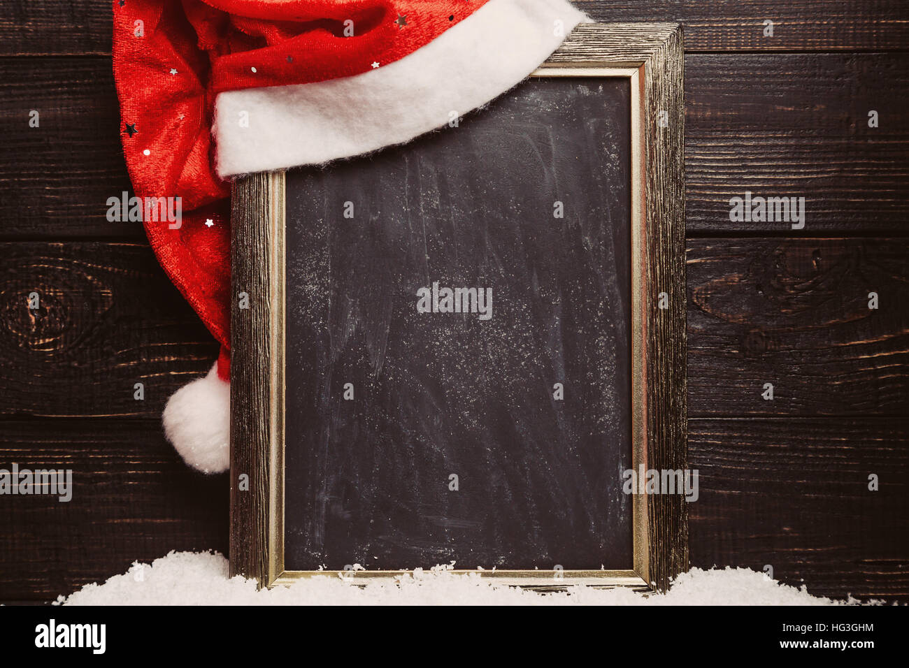 Red Santa hat sulla parte sporca della lavagna con la neve. Telaio con copyspace, sullo sfondo di Natale Foto Stock