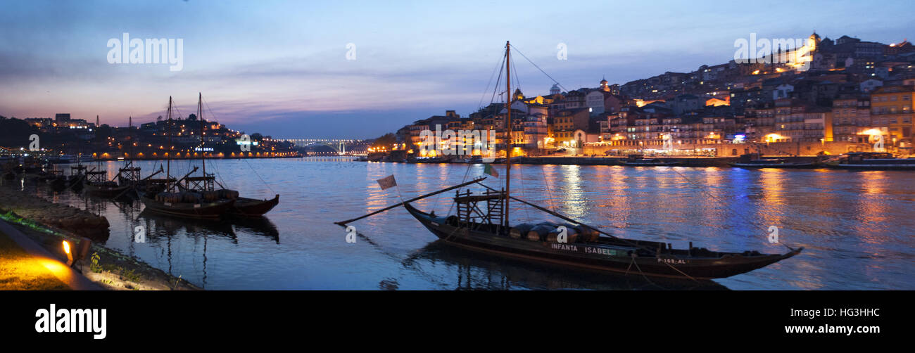 Portogallo: barche dopo il tramonto e la notte skyline del Porto con vista del fiume Douro tra le città di Porto e di Vila Nova de Gaia Foto Stock