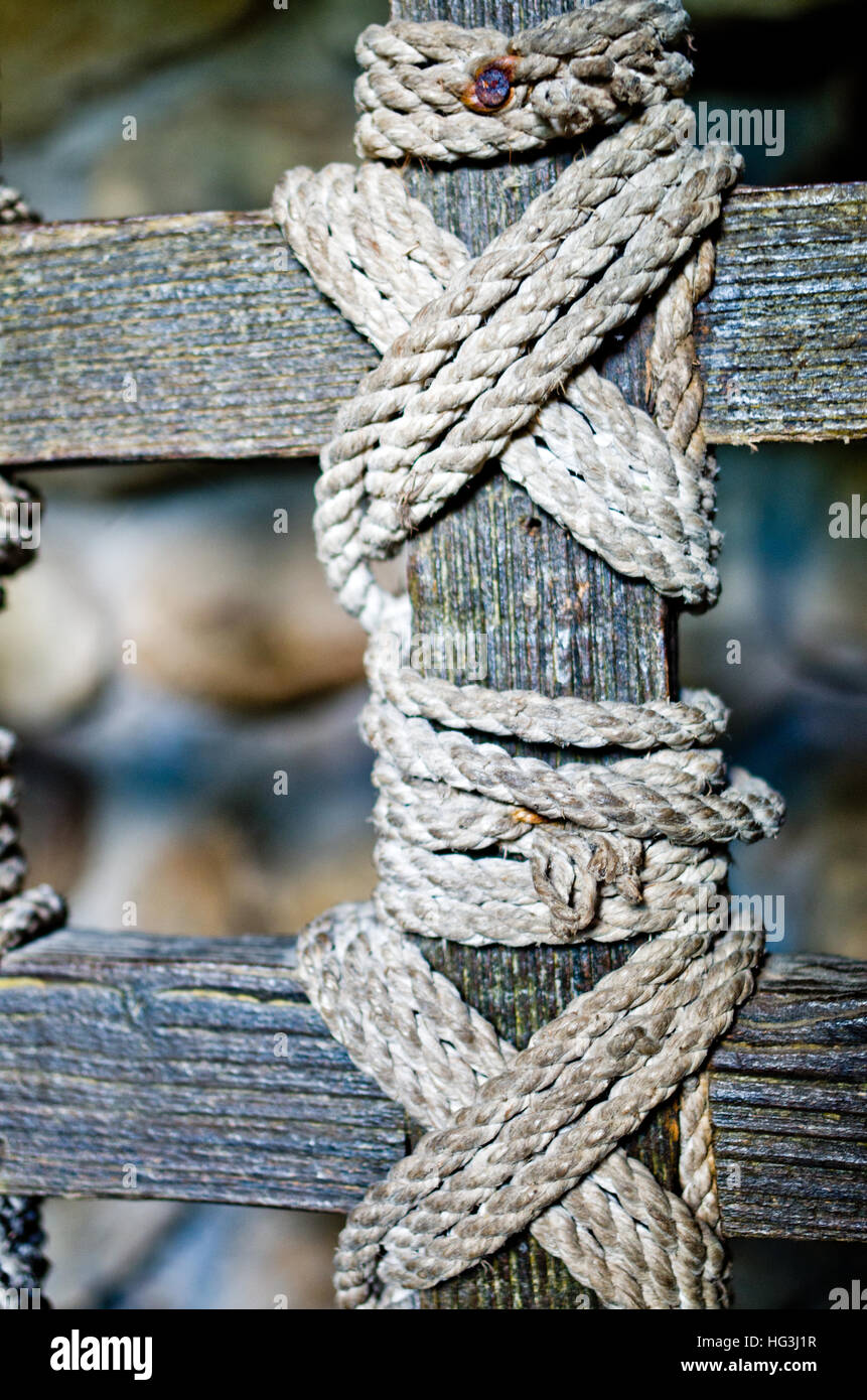 I nodi di una vecchia corda che tiene insieme dei listelli di legno di una ringhiera di protezione Foto Stock