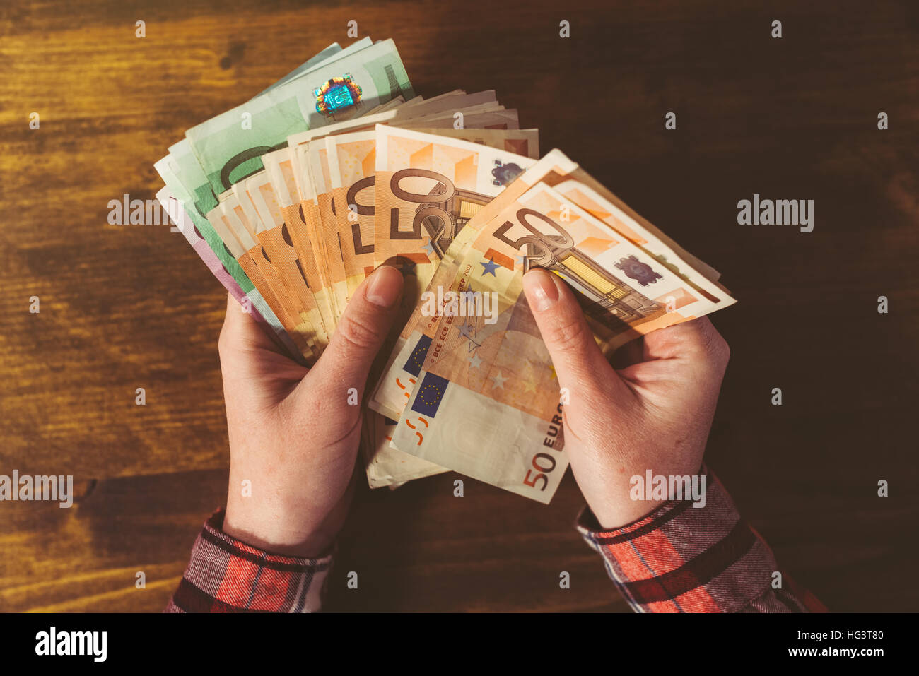 Mani femminili il conteggio di grandi quantità di valuta euro banconote in contanti, vista dall'alto al di sopra di scrivania da ufficio Foto Stock