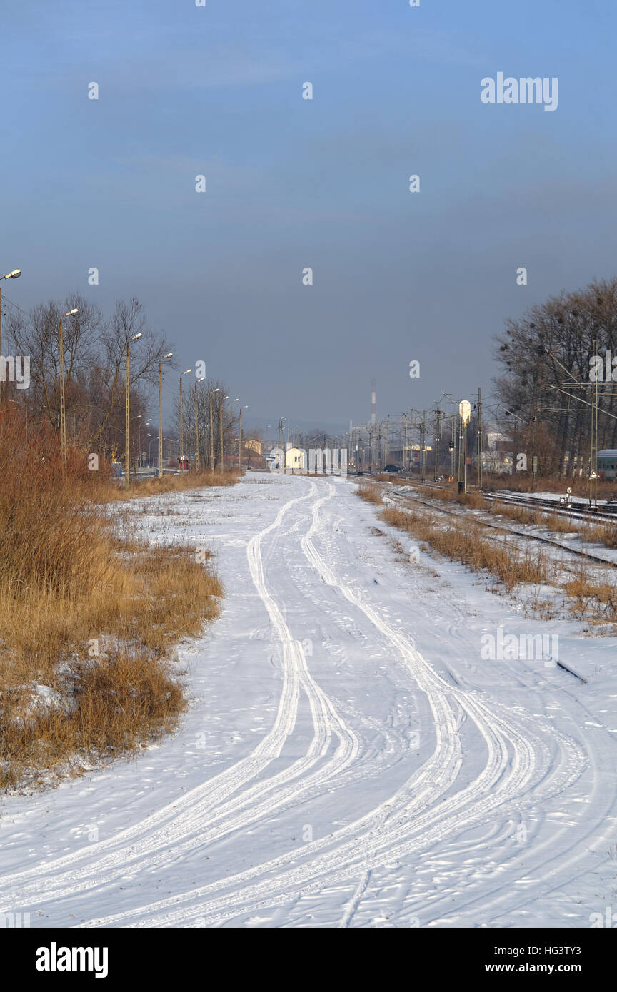 Tracce di pneumatici sulla strada innevata accanto alla stazione ferroviaria Foto Stock