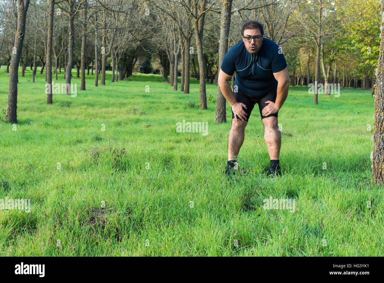 Astratto e concettuale, stanchi stanchi uomo nei boschi. L'uomo oppresso, riposo dopo una corsa nei boschi, appoggiata contro un albero. Foto Stock