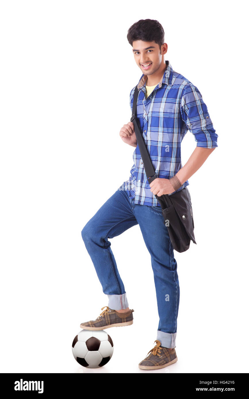 Ritratto di sorridente giovane studente in piedi con un piede su un campo di calcio e il trasporto di borsa a mano Foto Stock