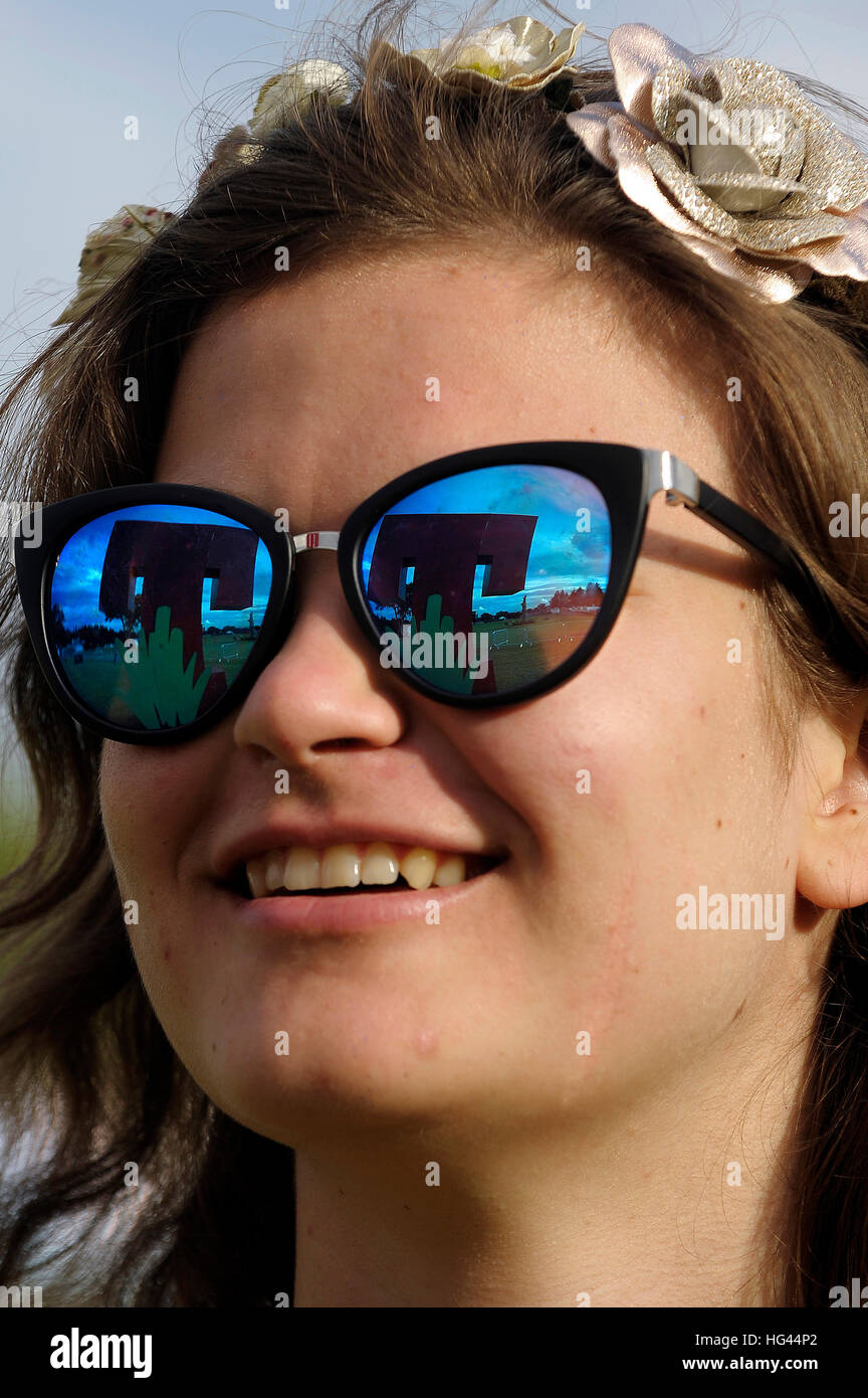 Una ventola femmina ha il logo del 2016 T nel Parco Festival si riflette nei suoi occhiali da sole come lei arriva all'evento. Foto Stock