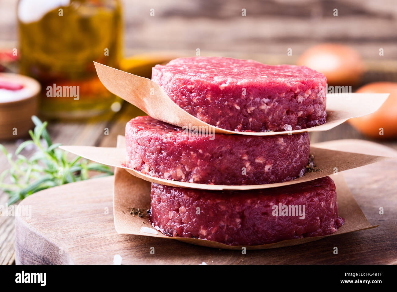 Materie organiche di macinato di manzo, polpette rotonde per realizzare in casa burger sul tagliere di legno Foto Stock