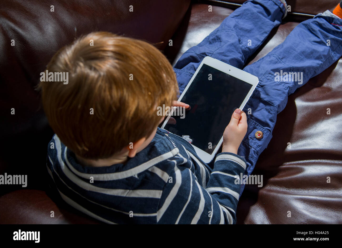 Bambino utilizzando la tecnologia. 5 anno vecchio ragazzo con un computer tablet o iPad Foto Stock