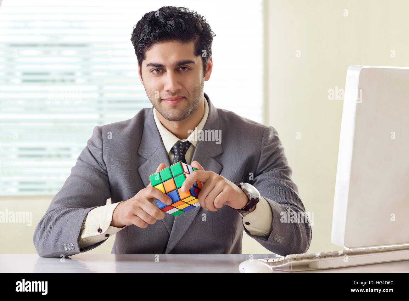 Imprenditore risolvere il cubo di Rubik puzzle Foto Stock