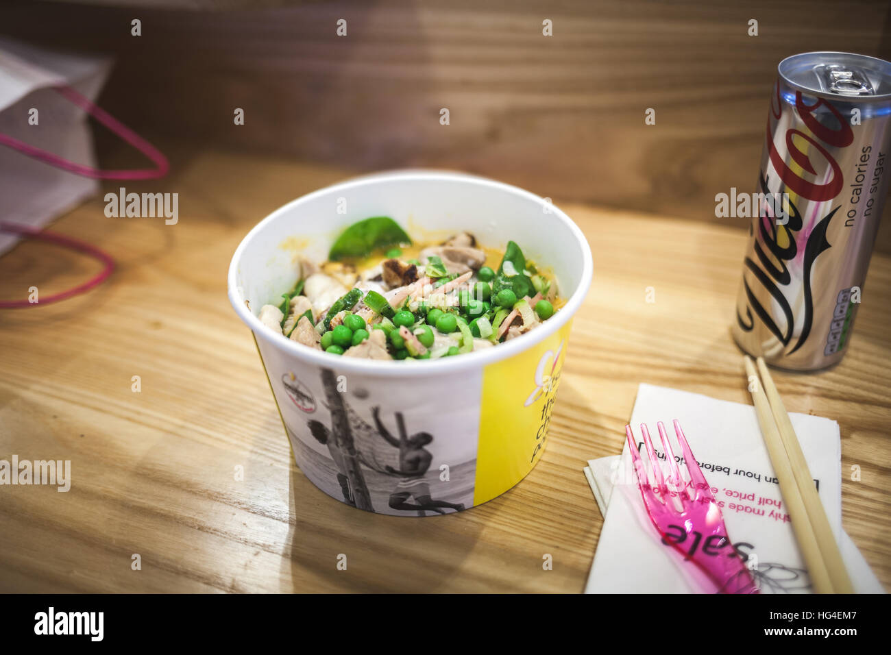 Un recipiente di cartone di Thai zuppa di pollo su un ristorante in legno tabella Foto Stock