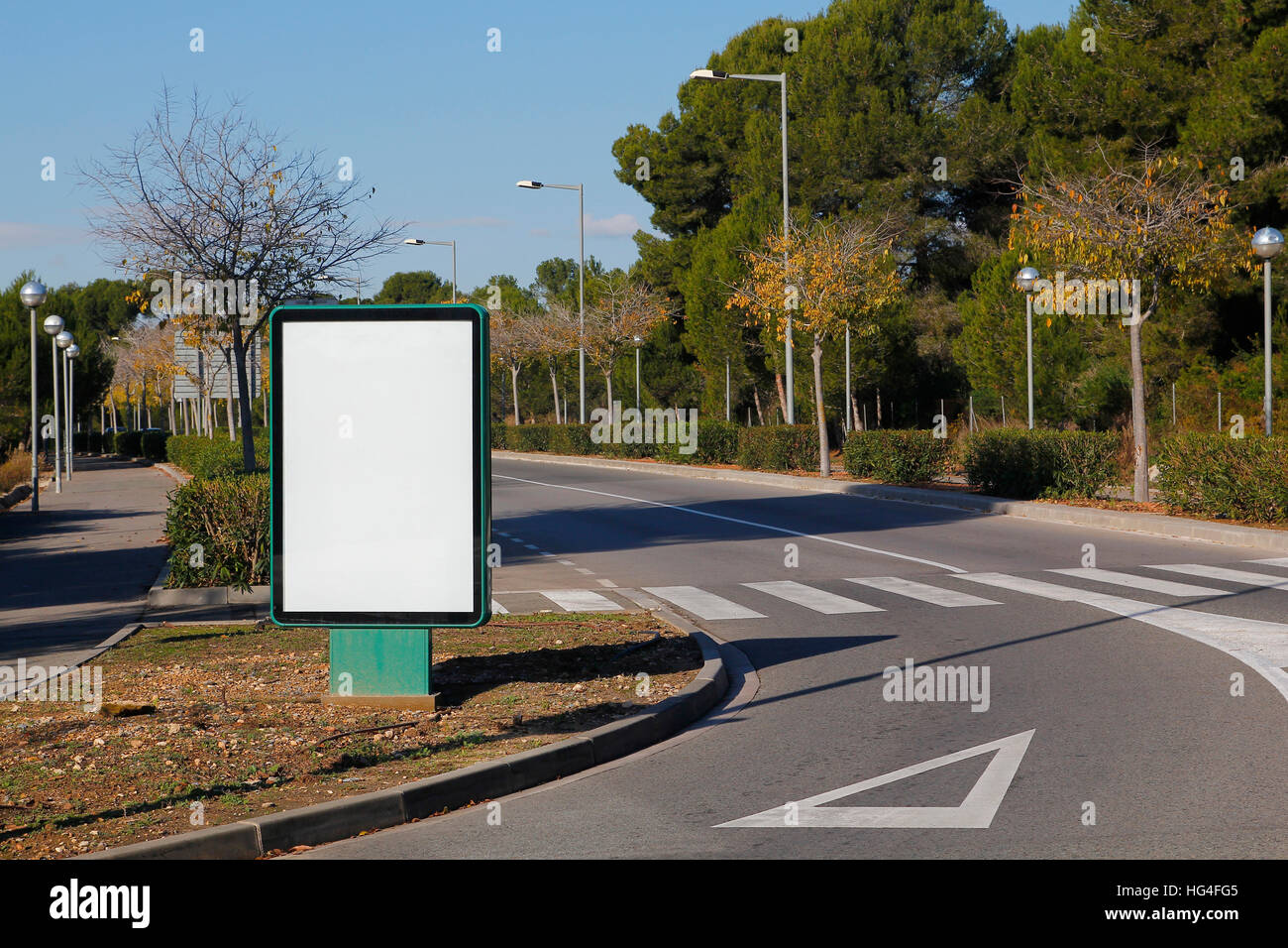 Tabellone vuoto in una strada verde, con dare modo segno in asfalto Foto Stock