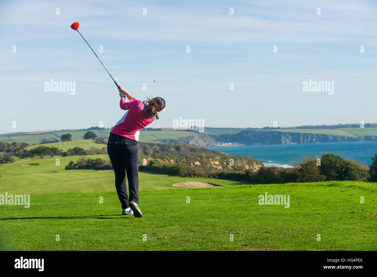 Un giovane giocatore di golf femminile di rinvio off in corrispondenza del primo foro. Foto Stock