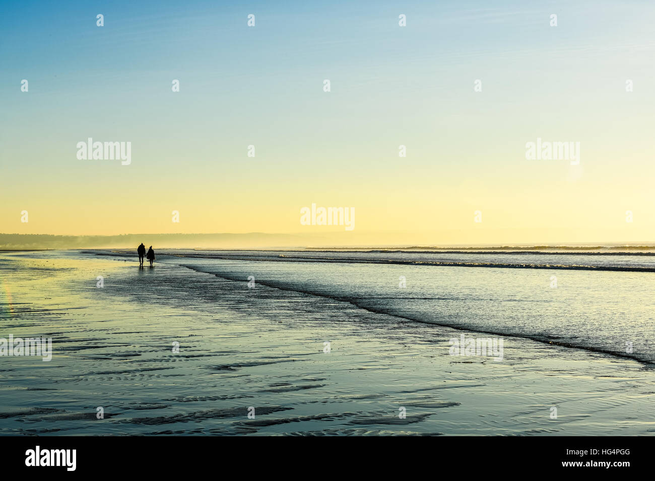 Una giovane coppia in amore tenendo le mani su una spiaggia al tramonto. Foto Stock