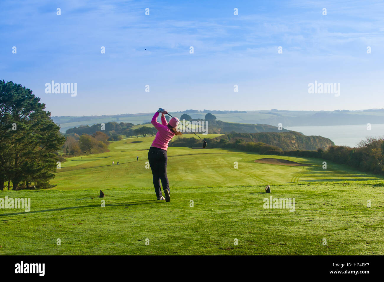 Un giovane giocatore di golf femminile di rinvio off in corrispondenza del primo foro. Foto Stock