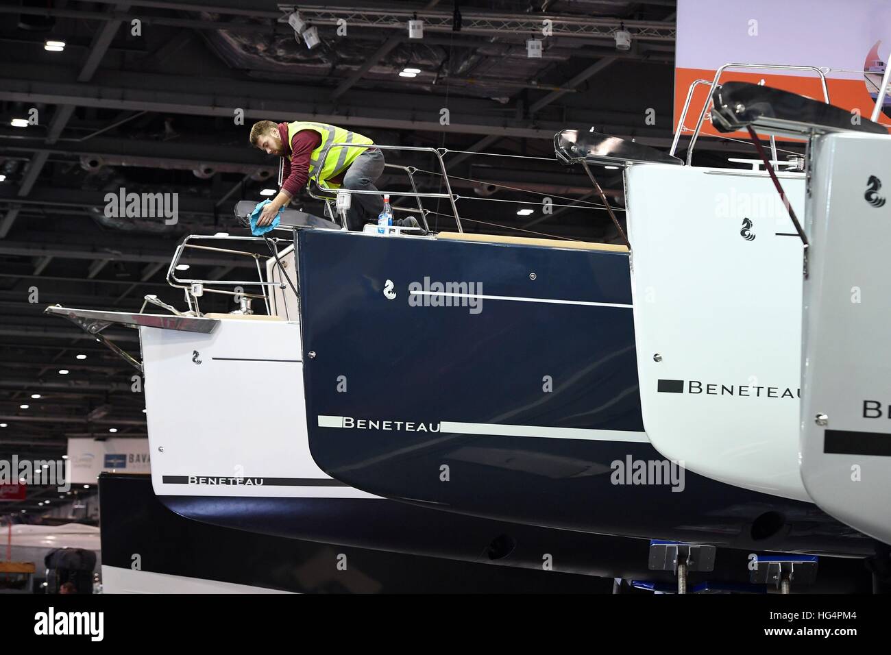 Un membro del personale si applica le regolazioni finali ad una barca sul Beneteau stand, davanti al London Boat Show presso il centro ExCel di Londra. Foto Stock