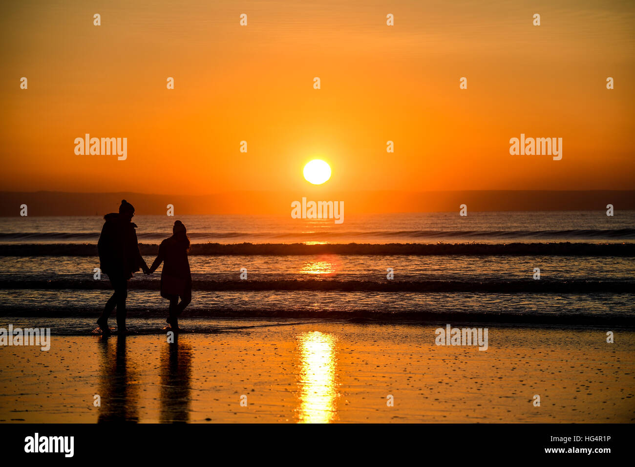 Una giovane coppia in amore tenendo le mani su una spiaggia al tramonto. Foto Stock