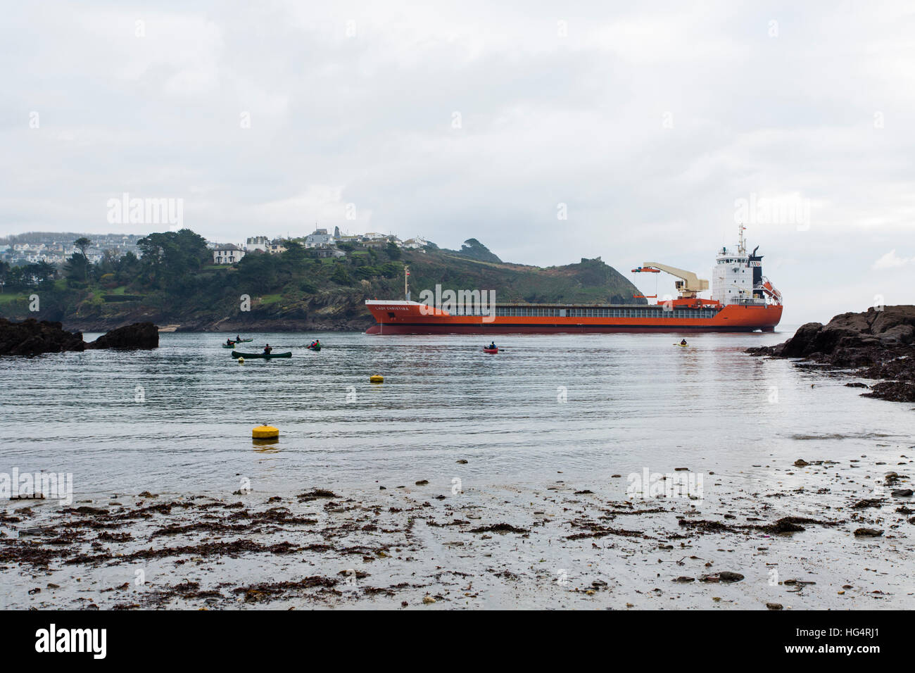 Una nave portacontainer entra nella foce del fiume Fowey estuario passato Readymoney Cove nel Fowey, Cornwall. Sea Kayakers guardano. Foto Stock