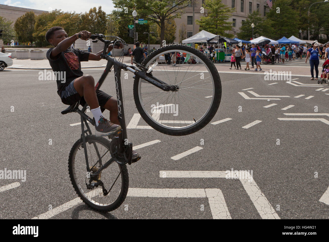 Ragazzo afro-americano di eseguire un wheelie in bicicletta - Washington DC, Stati Uniti d'America Foto Stock