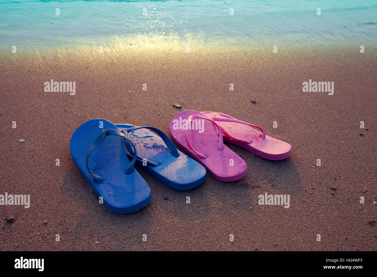 Romantica spiaggia scena. Maschi e femmine di flip flop sandals sulla spiaggia di sunrise Foto Stock