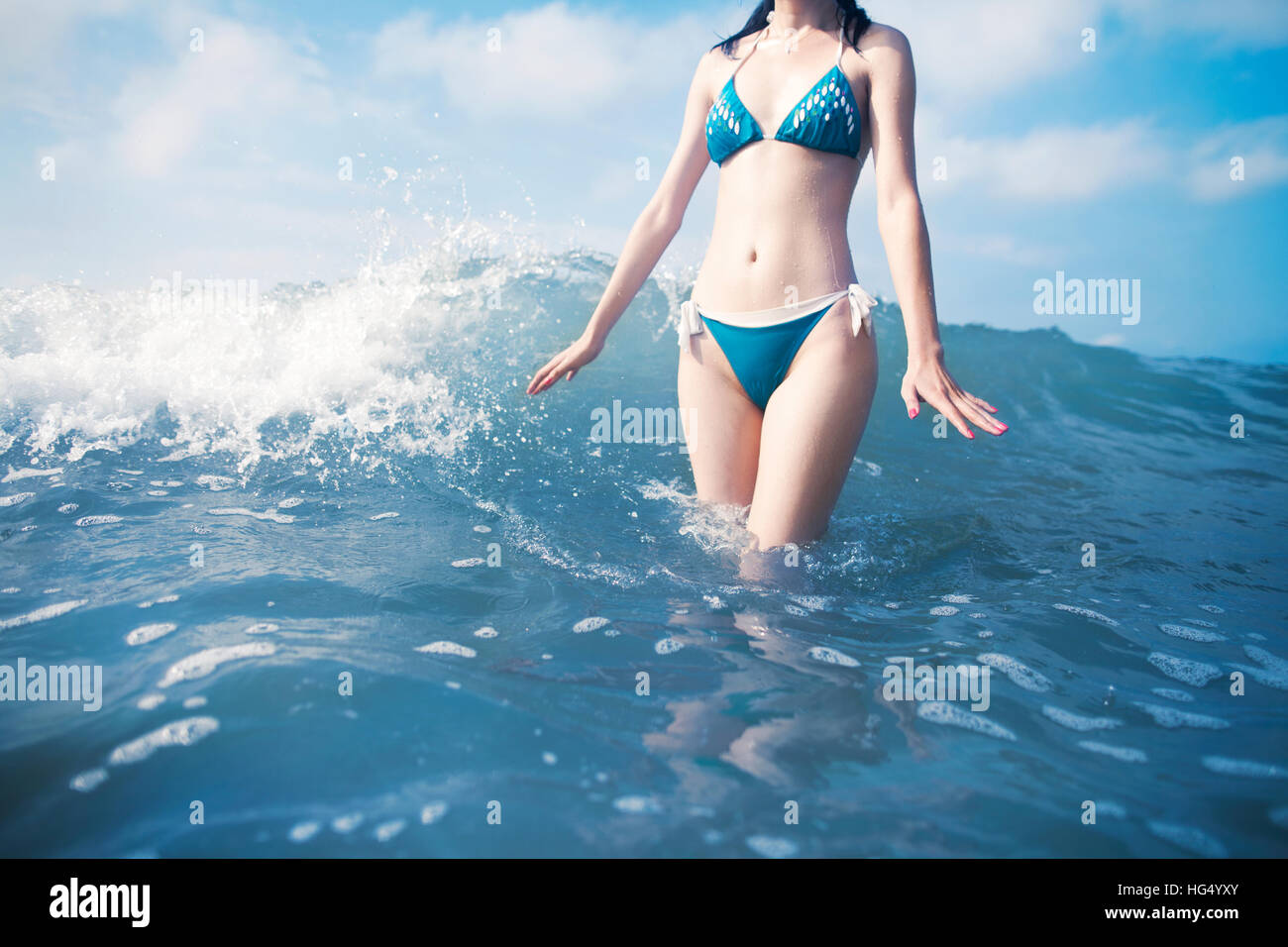 La donna in piedi di onde in spiaggia Foto Stock
