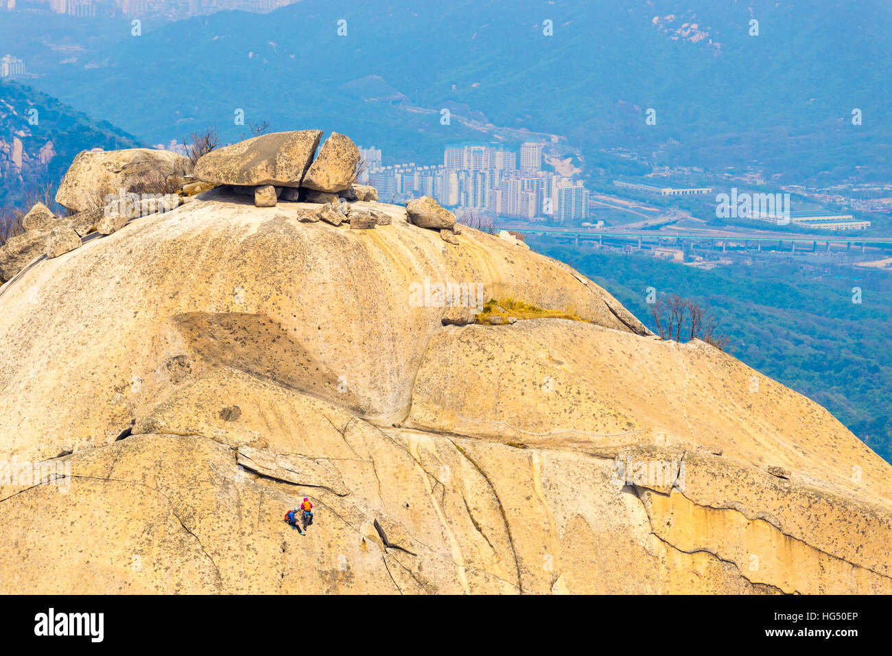 Gli alpinisti Insubong arrampicata su roccia, la seconda vetta più alta in corrispondenza Bukhansan montagna con vista della città sottostante in Seoul Sud Foto Stock