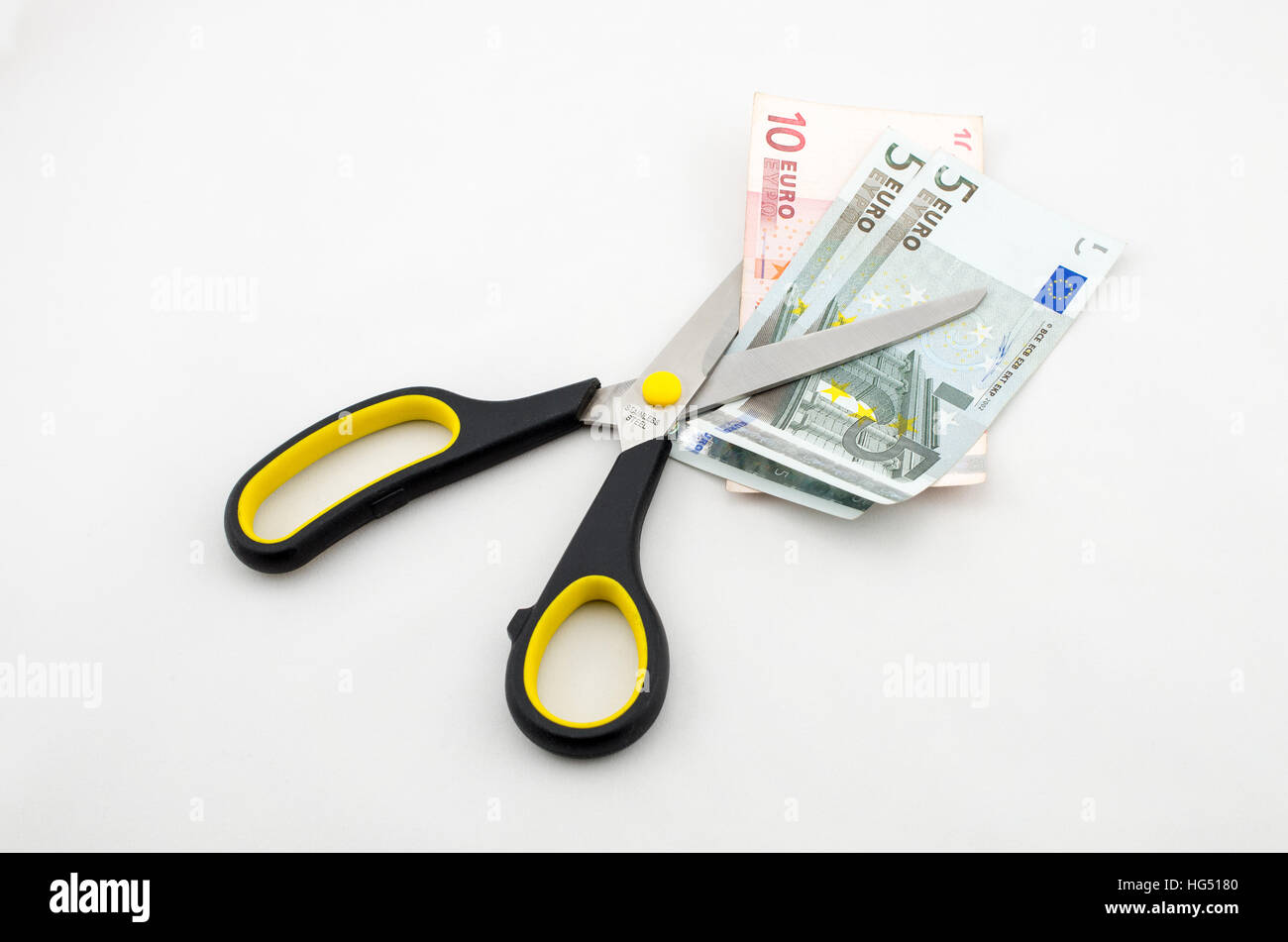 Nero con forbici elemnts giallo il taglio di più di banconote in euro Foto Stock