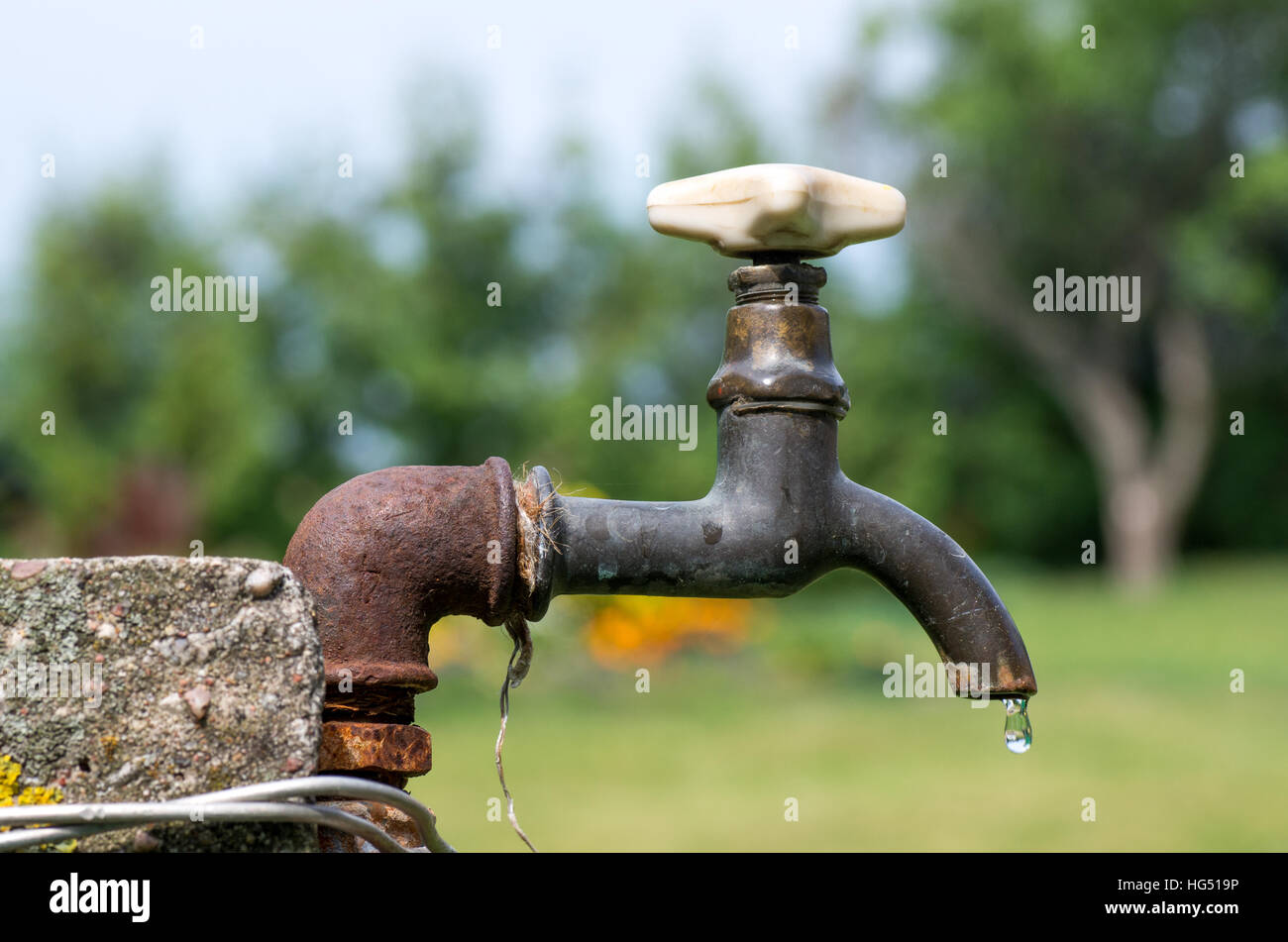 Un vecchio arrugginito rubinetto di acqua in giardino. Foto Stock