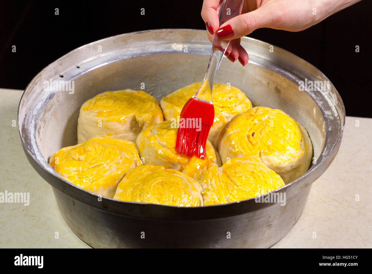 Giovane donna la cottura a casa tradizionale pane di festa. Ella mise il vassoio in forno caldo. Foto Stock