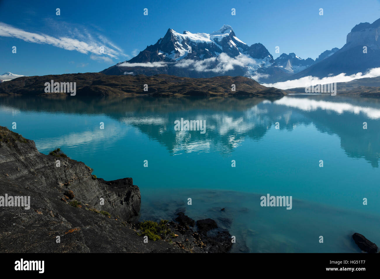 Cancellazione di nebbia sul Lago Pehoe. Poche nuvole basse rimangono, oscurando la base del Paine Grande. Le acque cristalline del lago di fornire uno specchio-simili riflettono Foto Stock