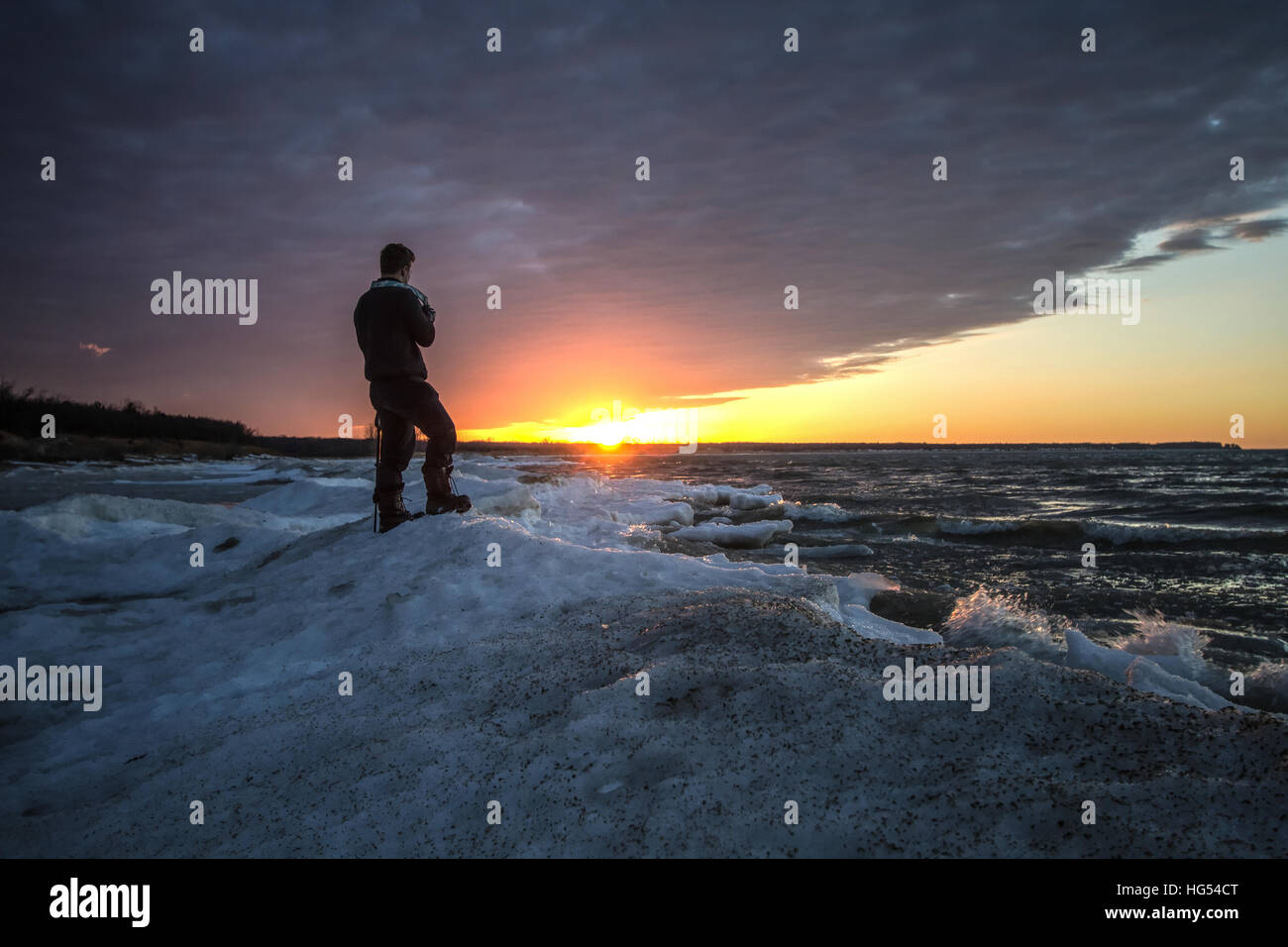 La fotografia d'inverno. Fotografo maschio all'aperto in piedi nella neve sulla riva di un lago ghiacciato. Porto Austin, Michigan. Foto Stock