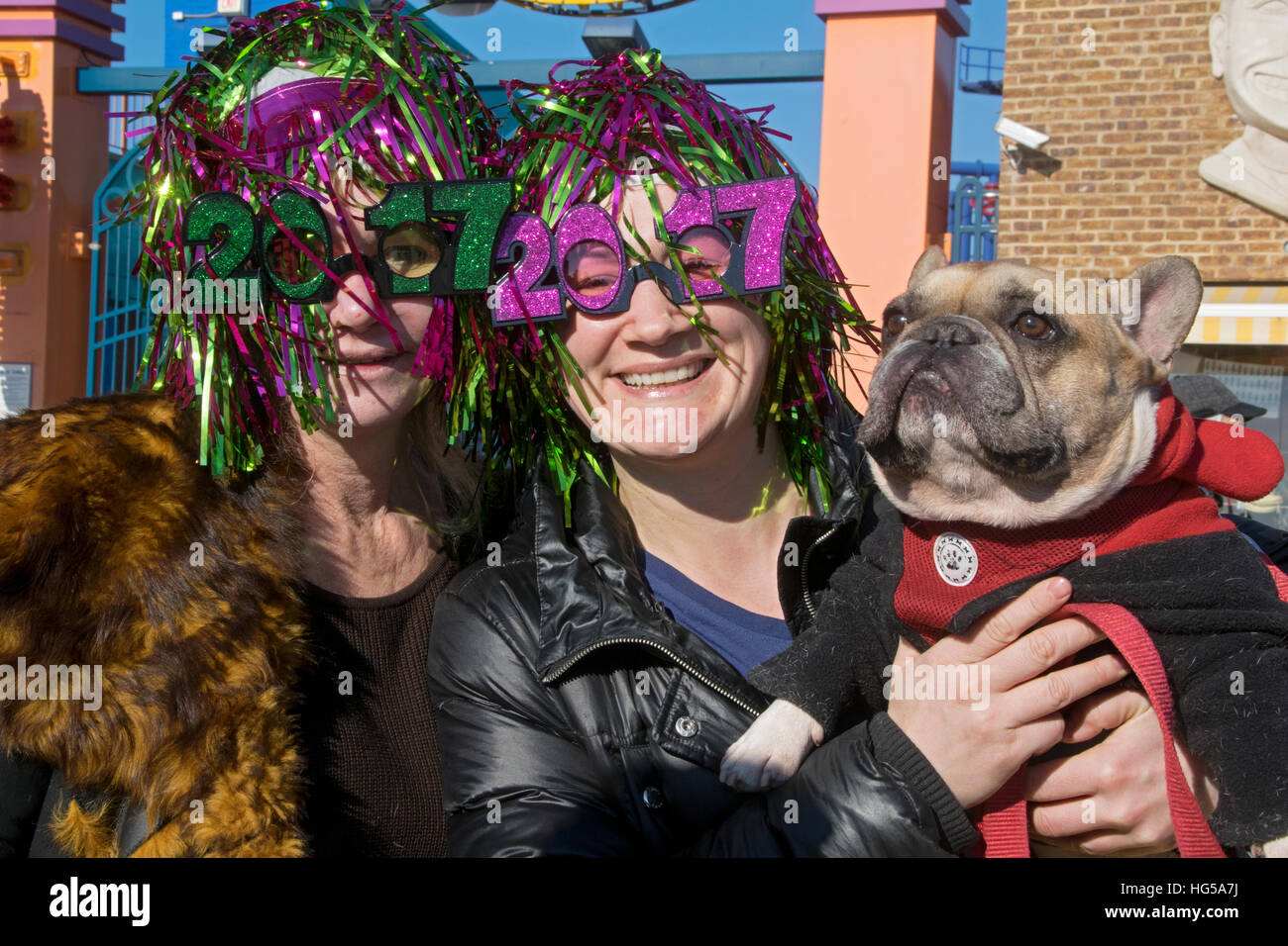 2 donne nel 2017 occhiali colorati e parrucche posano con il loro cane all'orso polare annuale del club di nuoto invernale, Coney Island Brooklyn NYC Foto Stock