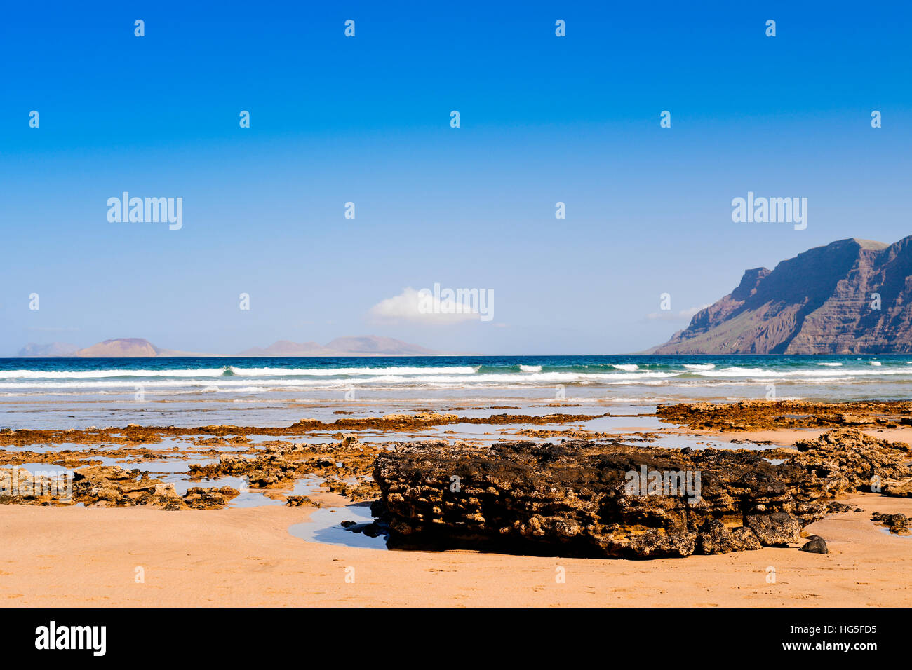 Una vista della spiaggia di Famara a Lanzarote, Isole Canarie, Spagna, con il Famara massiccio a destra e La Graciosa isola in background Foto Stock