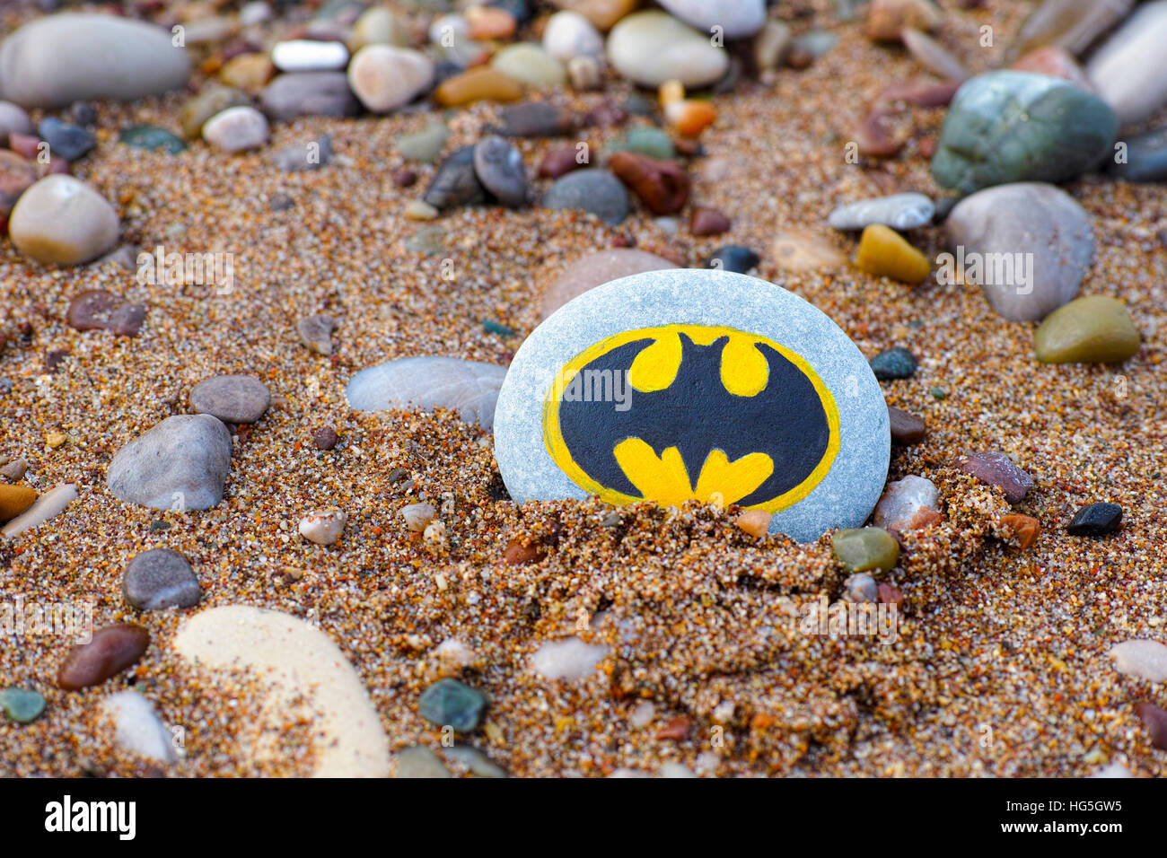 Paphos, Cipro - 22 novembre 2016 Sassi con segno dipinto Batman sdraiato sulla spiaggia con sabbia e pietre. Foto Stock