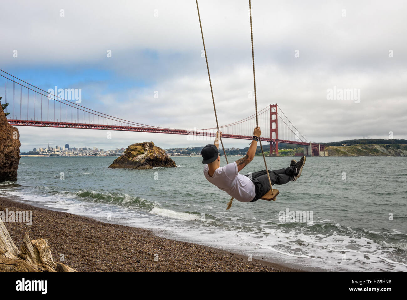 Giovane su un altalena con il Golden Gate Bridge e San Francisco in  background Foto stock - Alamy