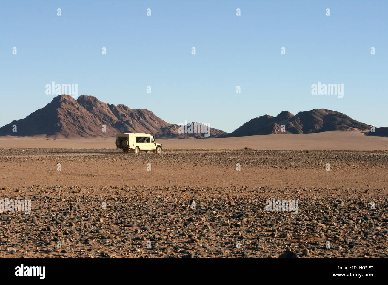 Un land rover aziona attraverso il deserto Nambian sotto il cielo limpido Foto Stock