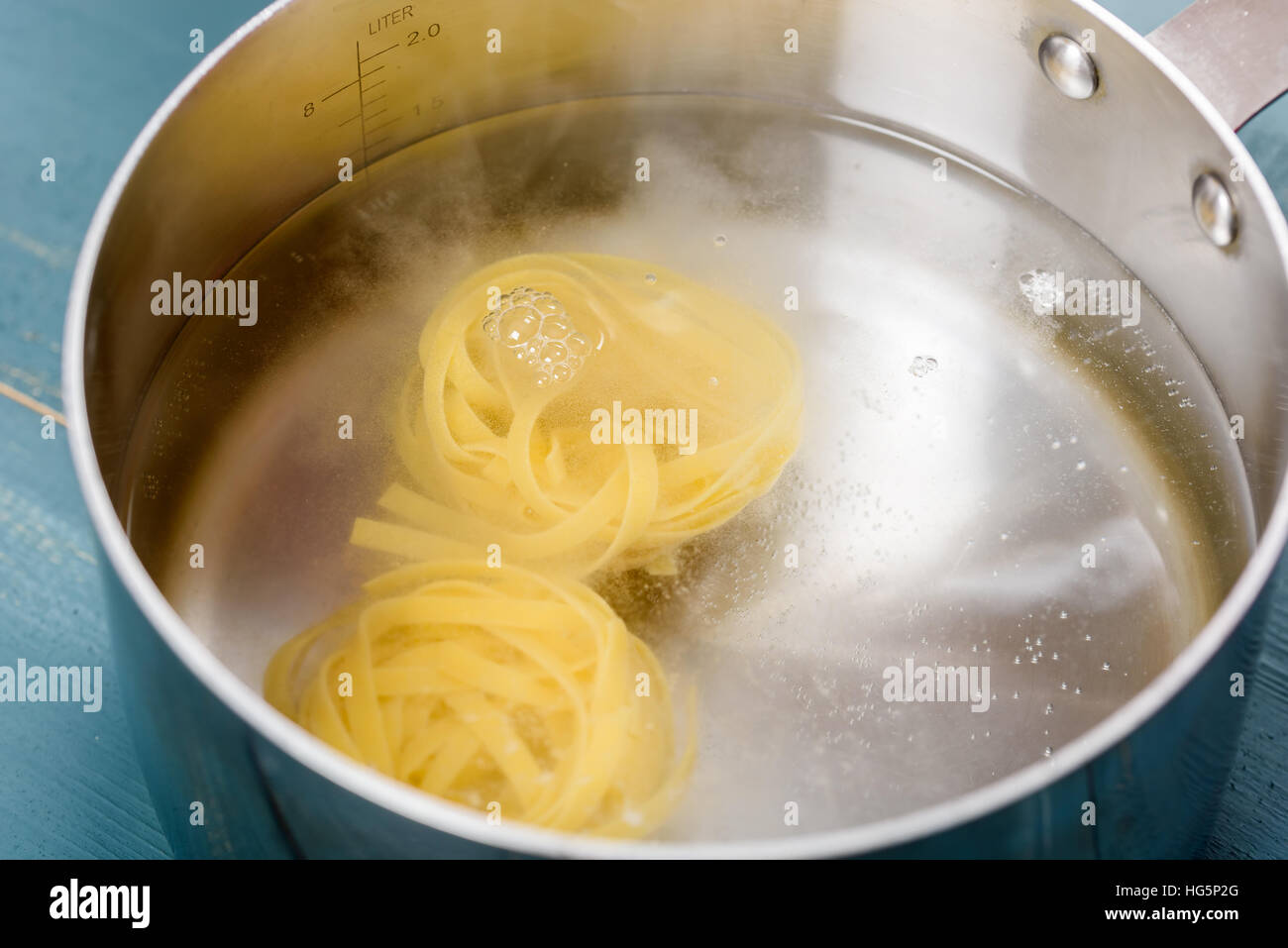 Aggiunta di tagliatelle in acqua calda per la pentola bollire Foto Stock