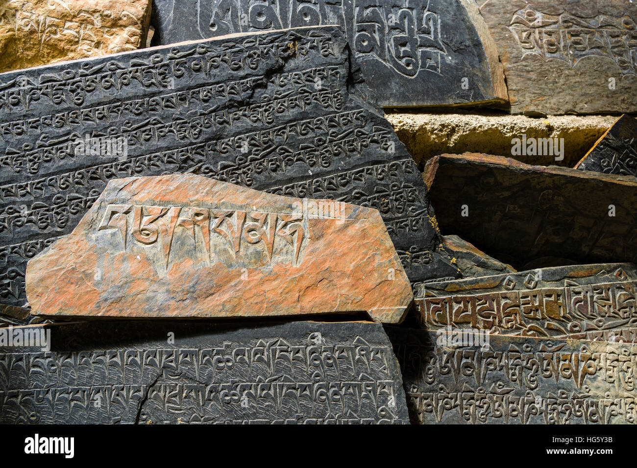 Mani pietre con inciso il mantra tibetano OM MANI PADME HUM sono impilati fino a una parete, Ngawal, Manang District, Nepal Foto Stock