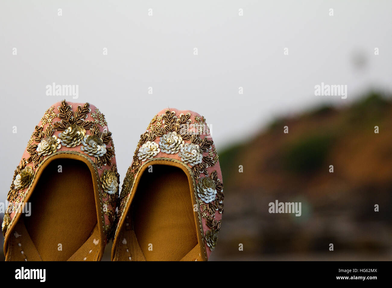 Coppia di tradizionale etnica indiana/pesca jutis rosa (scarpe donna) su una spiaggia in Goa, India con uno sfondo sfocato Foto Stock