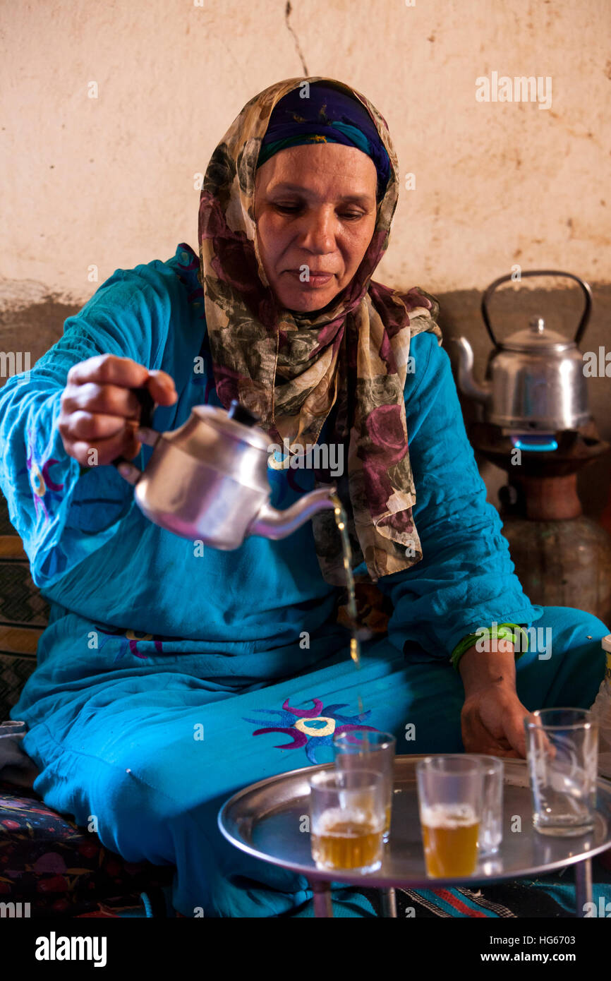 Ksar Elkhorbat, Marocco. Di mezza età Amazigh donna berbera versando il tè nel suo salotto. Foto Stock