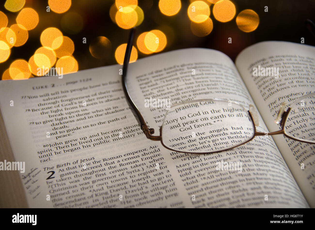 Una Bibbia aperta con evidenziato il versetto sulla storia di Natale con scintillante albero di Natale luci in background. Foto Stock