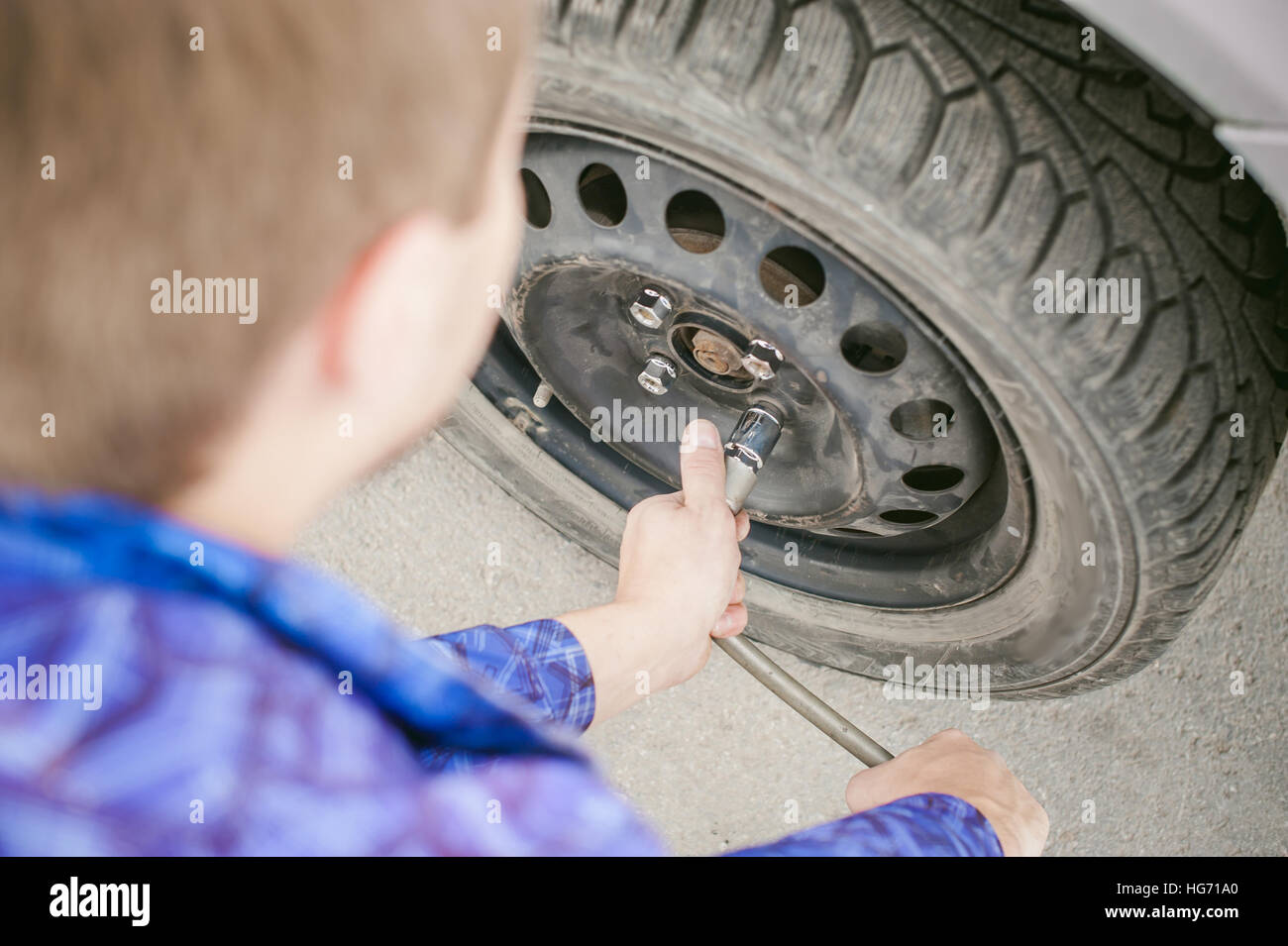 L'uomo la sostituzione di una ruota sulla strada. sul modo in cui vi è stata la rottura della ruota, forare necessarie per sollevare la vettura martinetto e togliere la ruota svitando le n Foto Stock