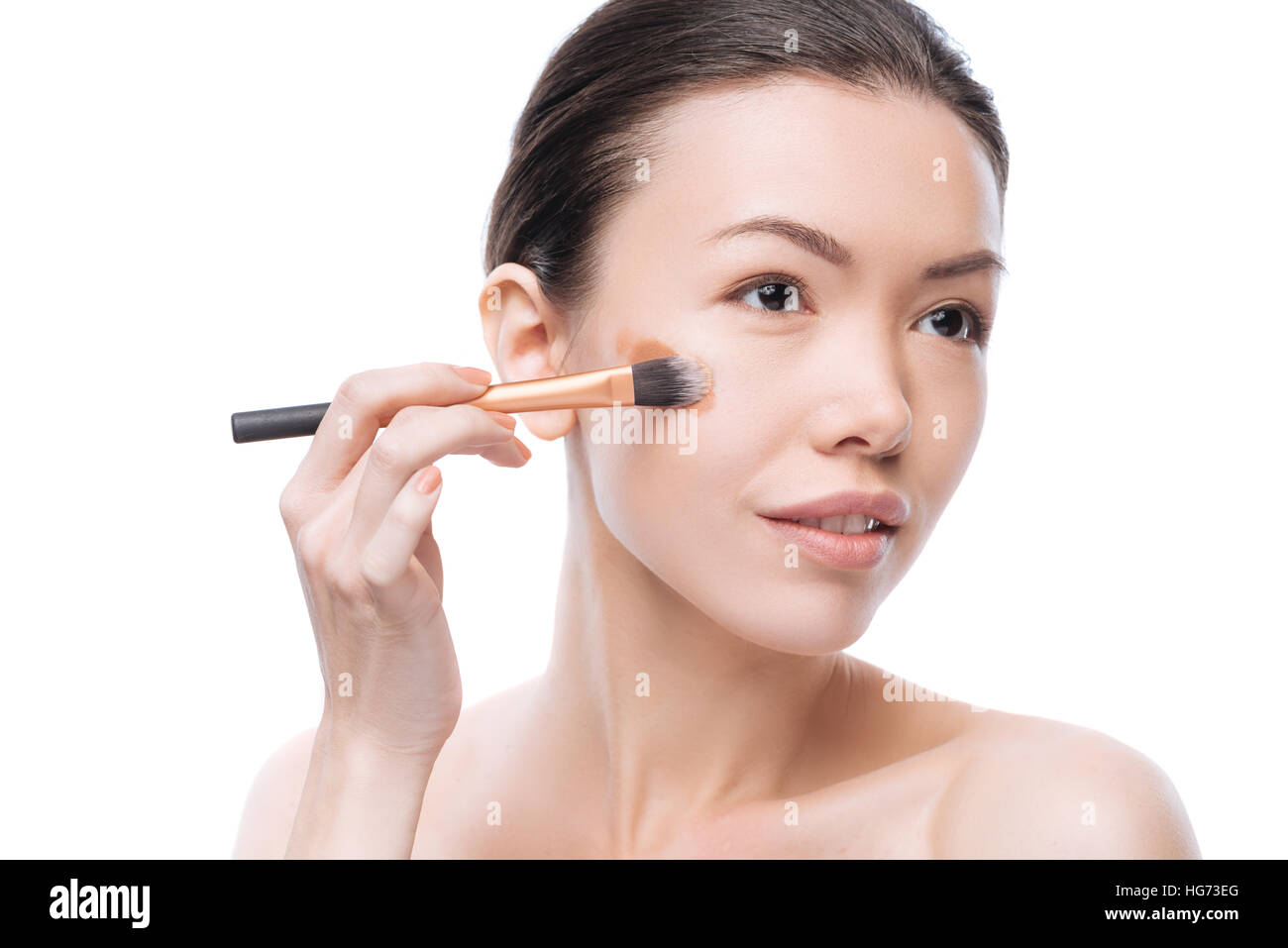 Felice giovane donna applicando fondotinta liquido Foto Stock