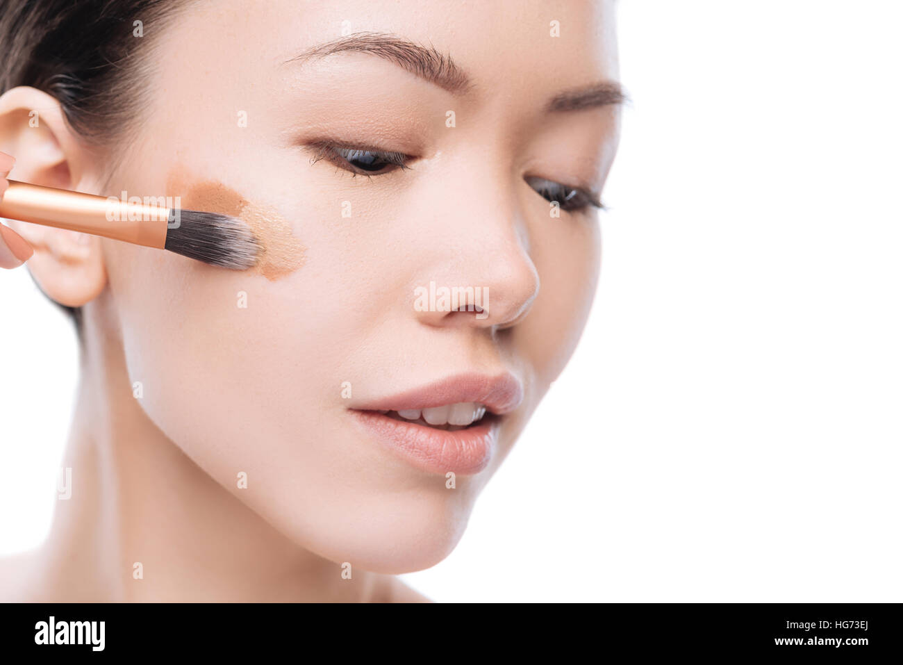 Bella donna asiatica di applicare diversi strati di fondazione di liquido Foto Stock