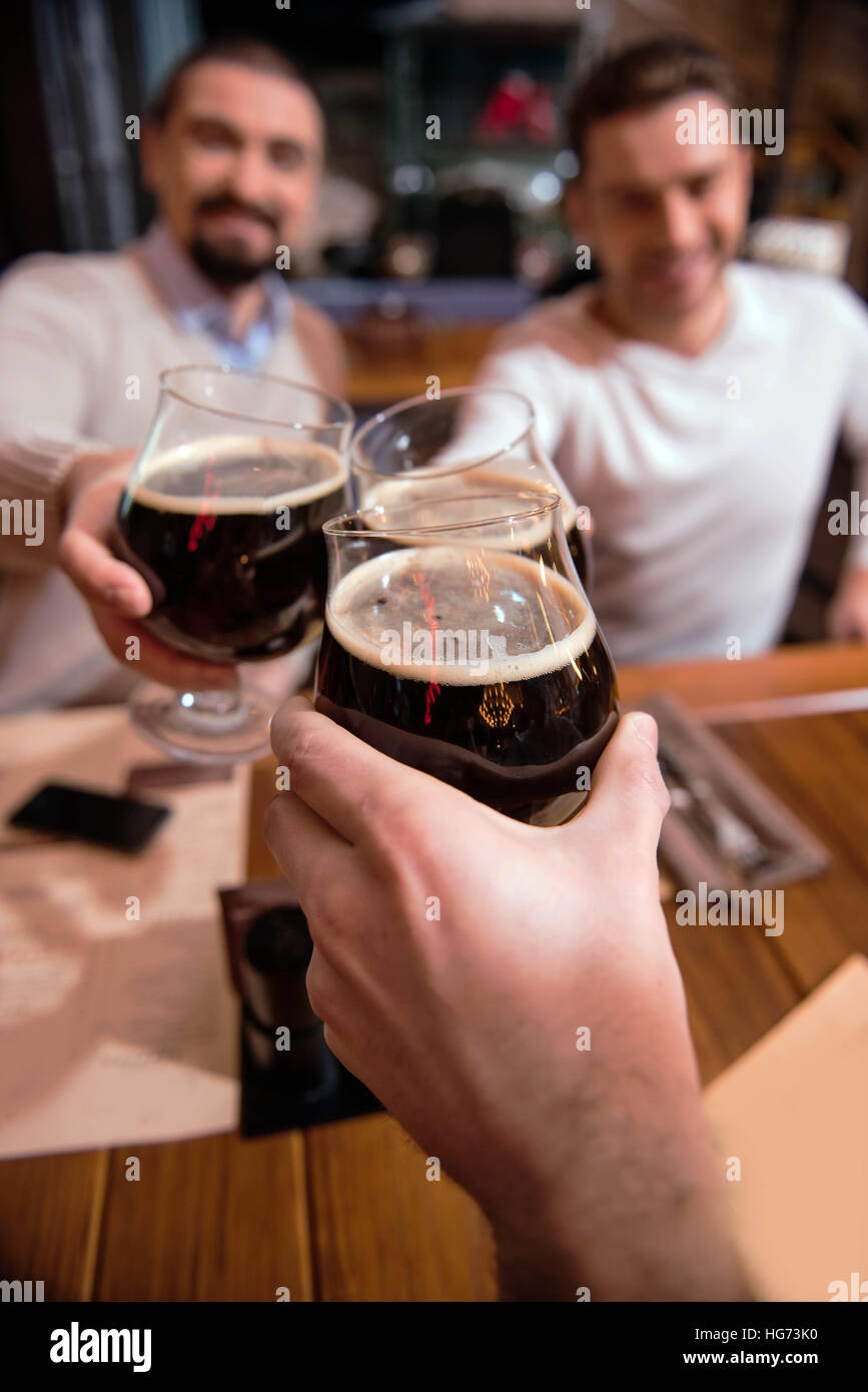 Bicchieri di birra tenuto da felice simpatici amici Foto Stock