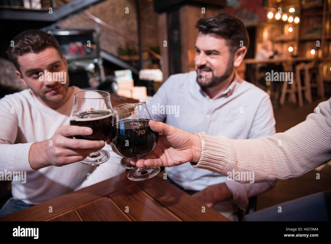 Bicchieri di birra scura in mani di felice uomini belli Foto Stock