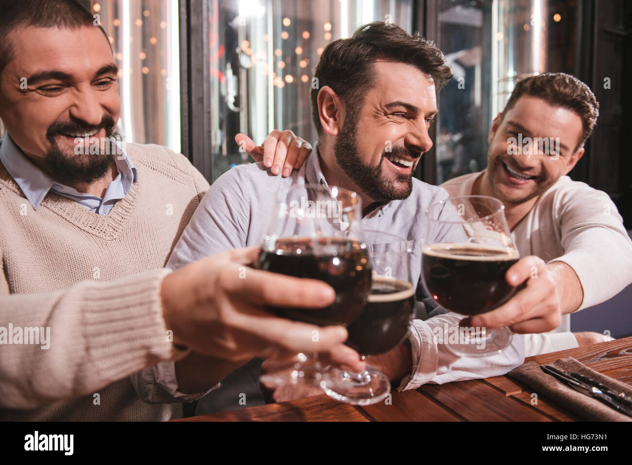 Happy amici maschi aumentando la loro bicchieri Foto Stock