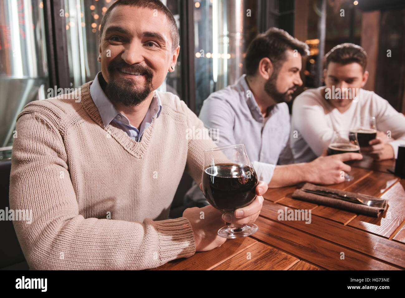 Bel uomo barbuto avente la birra con i suoi amici Foto Stock