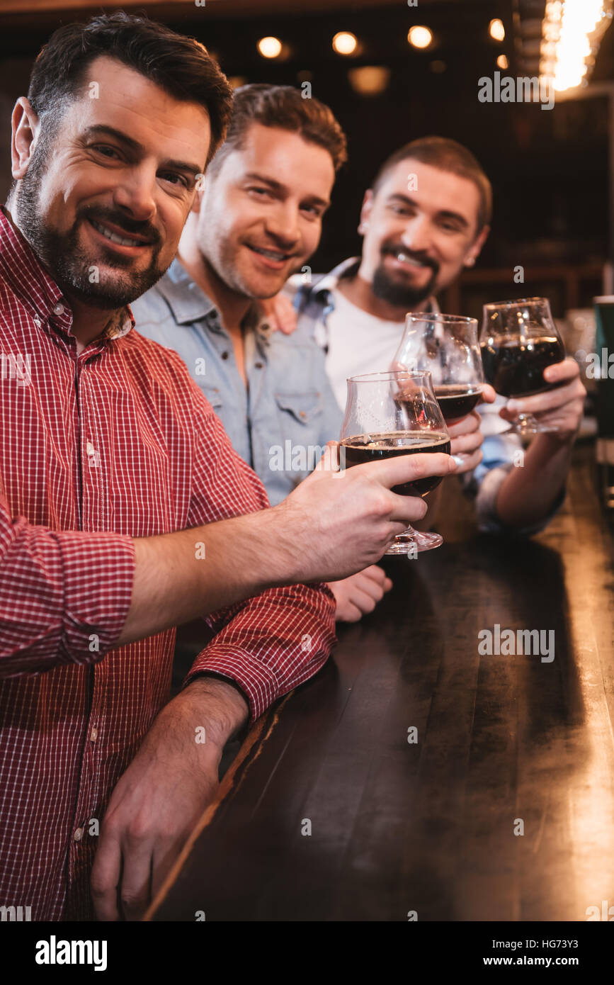 Allegro felici uomini aumentando il loro bicchieri Foto Stock